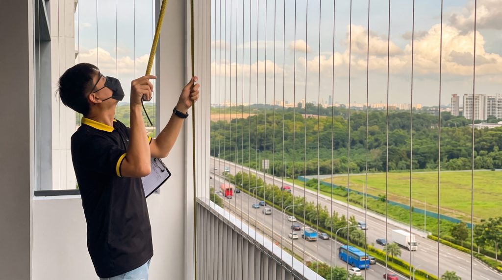 Consultant measuring a Singapore condo balcony for ZipScreen or outdoor roller blinds